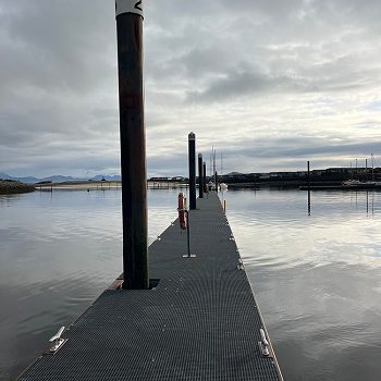 Pontŵn newydd gyda'r haul yn machlud yn y cefndir